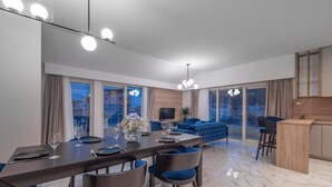 A modern dining area with a long table, blue chairs, and a chandelier. - Hotel Idila (Budva)