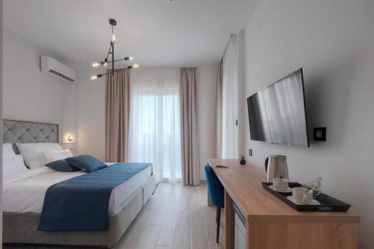 Una habitación de hotel moderna con cama, escritorio y televisor montado en la pared.