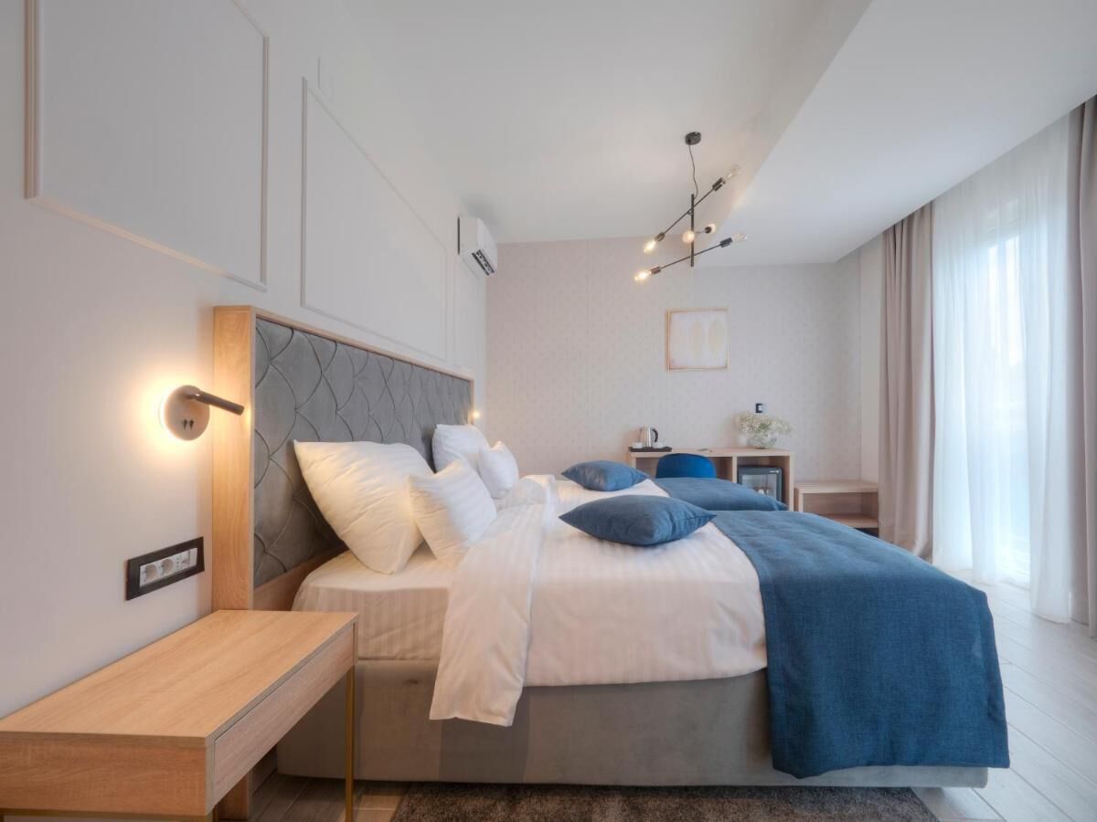 Et moderne soveværelse med en stor seng, sengeborde og en lampe i loftet.