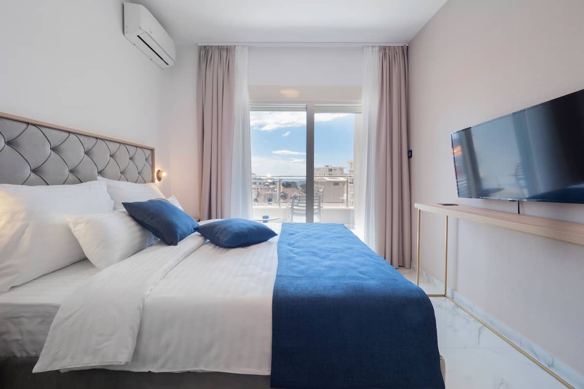 Una habitación de hotel con cama, televisión, ventana y aire acondicionado.