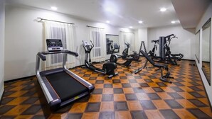 Une salle de sport équipée de divers appareils d’exercice, notamment des tapis de course, des vélos d’appartement et des appareils de musculation.