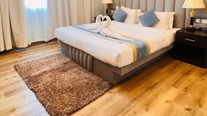 Une chambre moderne avec un grand lit, des lampes de chevet, un tapis moelleux et un luminaire au plafond.