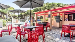 An outdoor patio area with red chairs and tables, umbrellas, and a pool in the background. - Residence Domaine de Valescure Saint-Raphaël (Saint-Raphaël)