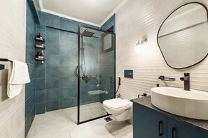A modern bathroom with a glass-enclosed shower, a white toilet, and a large round mirror. - Xuru Stays I Heliopolis 2 - 5 Min to Airport (Cairo)