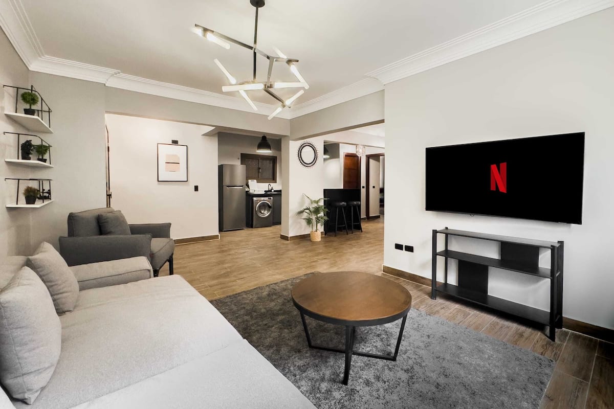 Ein modernes Wohnzimmer mit Sofa, Couchtisch und Wandfernseher.