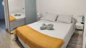 Une chambre à coucher comprenant un lit, une table de chevet, une commode, un tableau accroché au mur et une armoire.