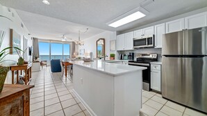 Una cocina amplia con armarios blancos, una isla grande y electrodomésticos de acero inoxidable.