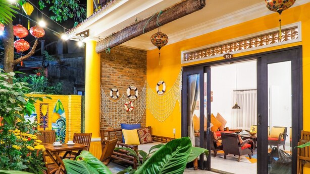 A cozy indoor space with a wooden table and chairs, a sofa, and a dining area. - Blue Beach Village (Da Nang)