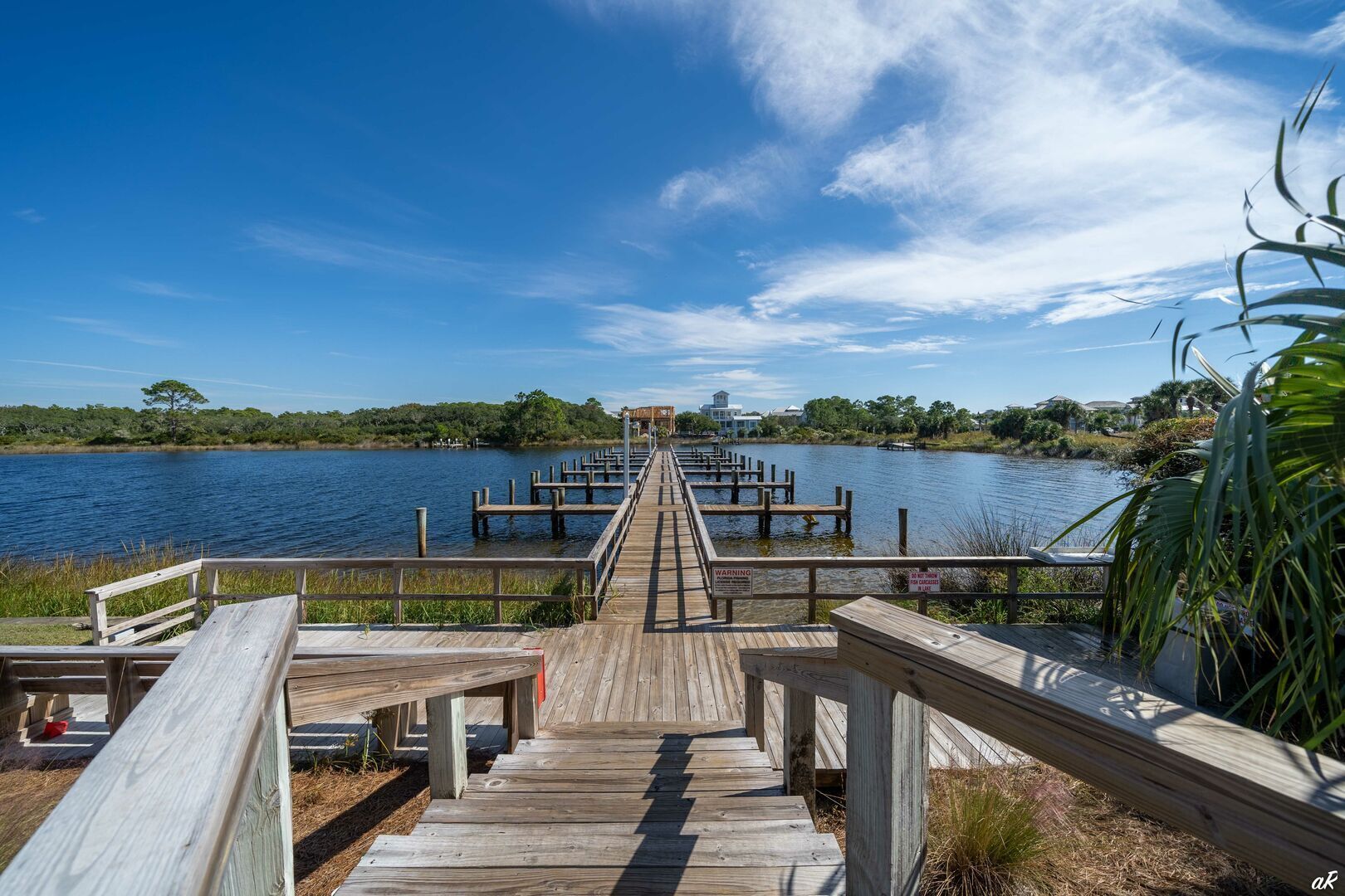 A wooden pier extending into a calm body of water, with a clear sky above.