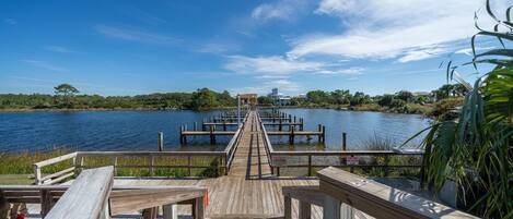 A wooden pier extending into a calm body of water, with a clear sky above.
