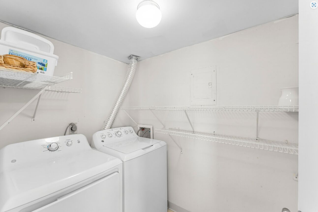 A laundry room with a washing machine, dryer, and shelves for storage.