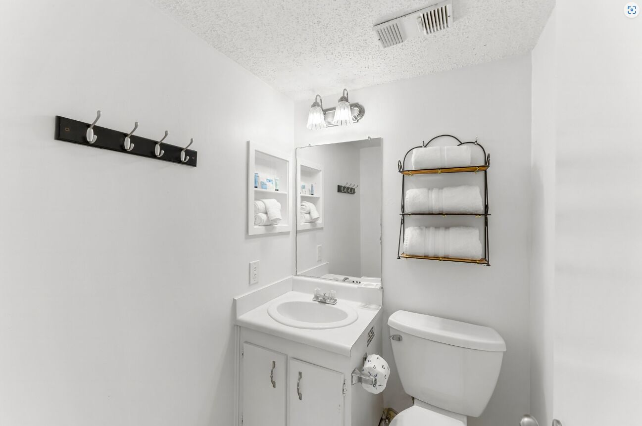 A modern bathroom with a white sink, toilet, and a towel rack.