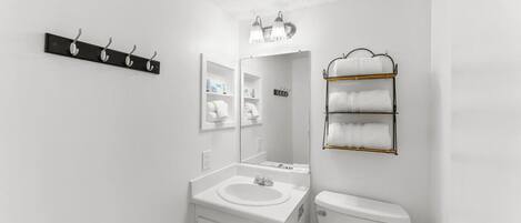 A modern bathroom with a white sink, toilet, and a towel rack.