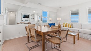 A modern living room with a dining table, chairs, a sofa, and a television. - The Hideaway at Ocean Isle Beach (Ocean Isle Beach)