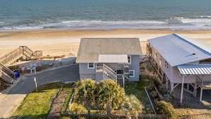 A beachfront property with a house, a covered porch, and a staircase leading to the beach. - The Hideaway at Ocean Isle Beach (Ocean Isle Beach)