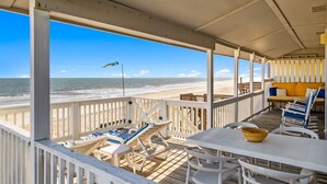 A beachside deck with lounge chairs, a table, and a view of the ocean. - The Hideaway at Ocean Isle Beach (Ocean Isle Beach)