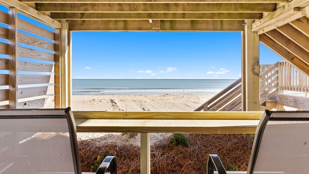 A beach view from a wooden structure with a clear sky. - The Hideaway at Ocean Isle Beach (Ocean Isle Beach)