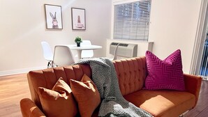 A living room with a brown sofa, a small table, and two framed pictures on the wall. - Nice 1-bedroom apartment in Marina del Rey (Marina del Rey)