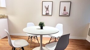 A dining area with a round table, four white chairs, and two framed pictures on the wall. - Nice 1-bedroom apartment in Marina del Rey (Marina del Rey)