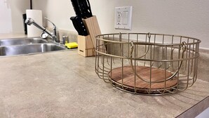 A kitchen counter with a wire basket holding a wooden cutting board, a knife block, and a faucet. - Nice 1-bedroom apartment in Marina del Rey (Marina del Rey)