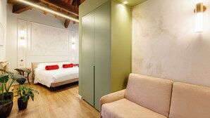 A hotel room with a bed, a sofa, a green wardrobe, and potted plants.