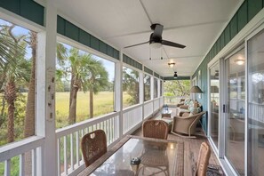 A covered porch with a glass railing, wicker furniture, and a ceiling fan. - 110 Sandpiper Run (Fripp Island)