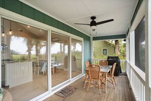 A covered patio with a table and chairs, a ceiling fan, and a sliding glass door leading to a kitchen area. - 110 Sandpiper Run (Fripp Island)