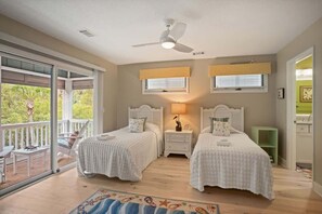 A bedroom with two beds, a ceiling fan, and a balcony with a view of greenery. - 110 Sandpiper Run (Fripp Island)