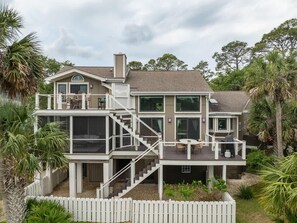 A multi-story house with a balcony, a staircase, and a white fence.
