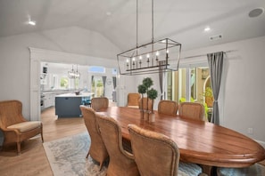 A dining area with a wooden table, wicker chairs, and a hanging light fixture. - 114 Sandpiper Run (Fripp Island)