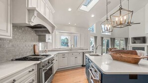 A modern kitchen with white cabinetry, a large island, and a skylight.