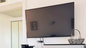 Eine Küchenzeile mit Kühlschrank, Kaffeemaschine, Mixer und einem Fernseher, der über der Arbeitsfläche angebracht ist.