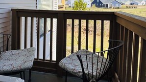 Ein überdachter Balkon mit zwei gemusterten Stühlen, einem kleinen Tisch und einem Heizgerät.