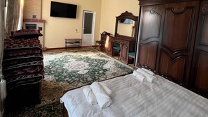 A hotel room with two beds, a large wooden wardrobe, a flat-screen TV, and a fireplace. - Sweet Home (Samarkand)