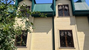 A building with a green roof and two ornate windows with metal bars. - Sweet Home (Samarkand)