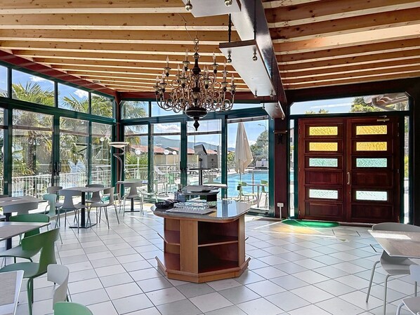 A spacious indoor area with a wooden ceiling, large windows, and a central table.