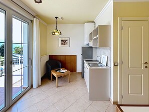 A compact kitchen with a sink, a chair, a table, and a ceiling light fixture.