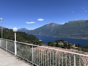 A coastal view with a clear sky, a mountain in the background, and a white railing in the foreground.