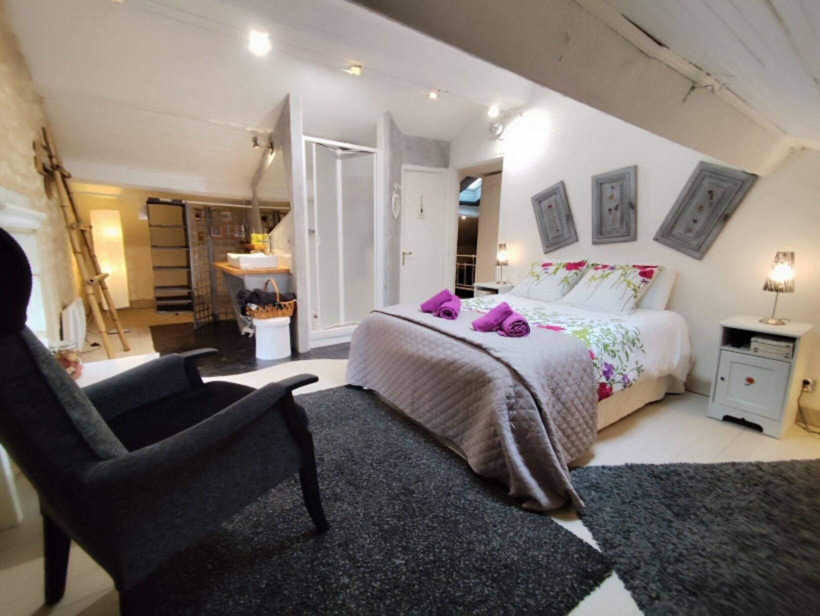 Een slaapkamer met een bed, een stoel, een nachtkastje en een kledingkast.