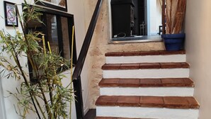 Eine Treppe mit weißen Stufen und einem schwarzen Geländer, die zu einem Raum mit einem schwarzen Kamin führt.