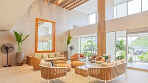 A spacious living area with wicker furniture, a large mirror, and a view of greenery outside.