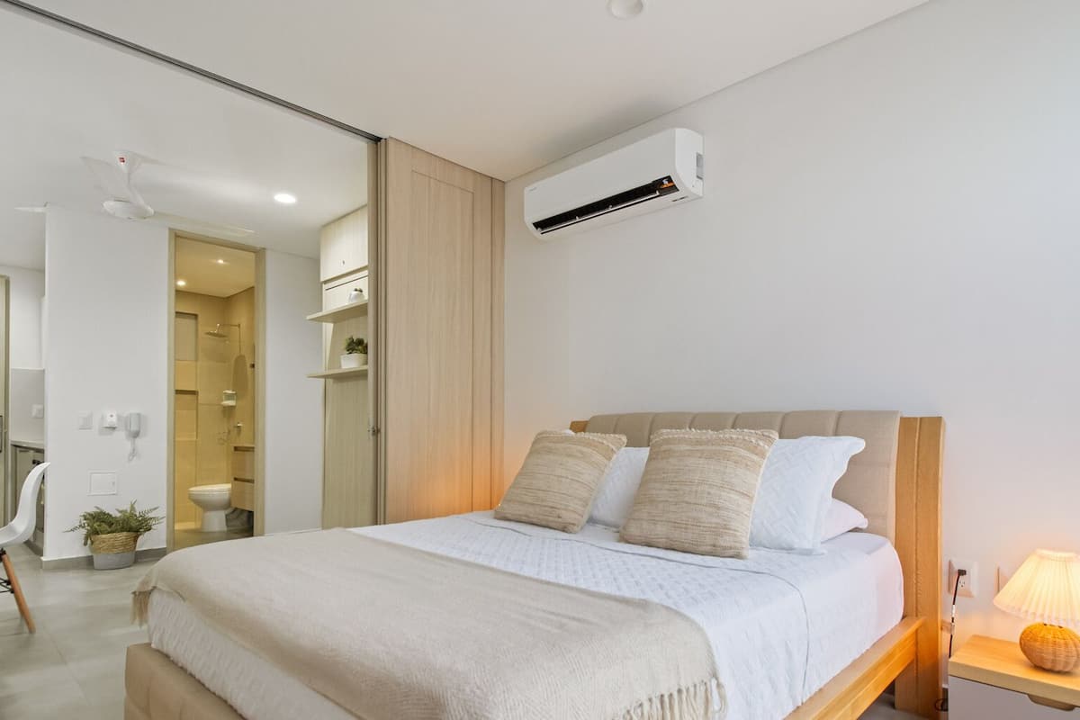 A bedroom with a bed, bedside table, and an air conditioning unit.
