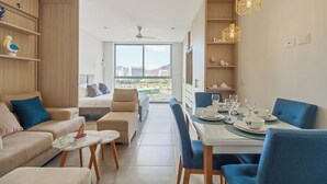 A modern living room with a dining area, large windows, and a view of the city.