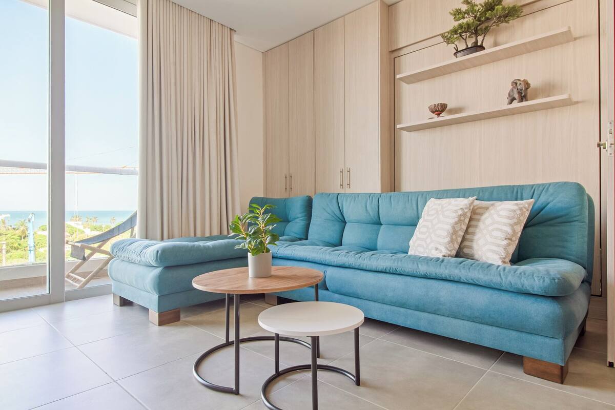 A modern living room with a blue sofa, a small round table, and a potted plant.