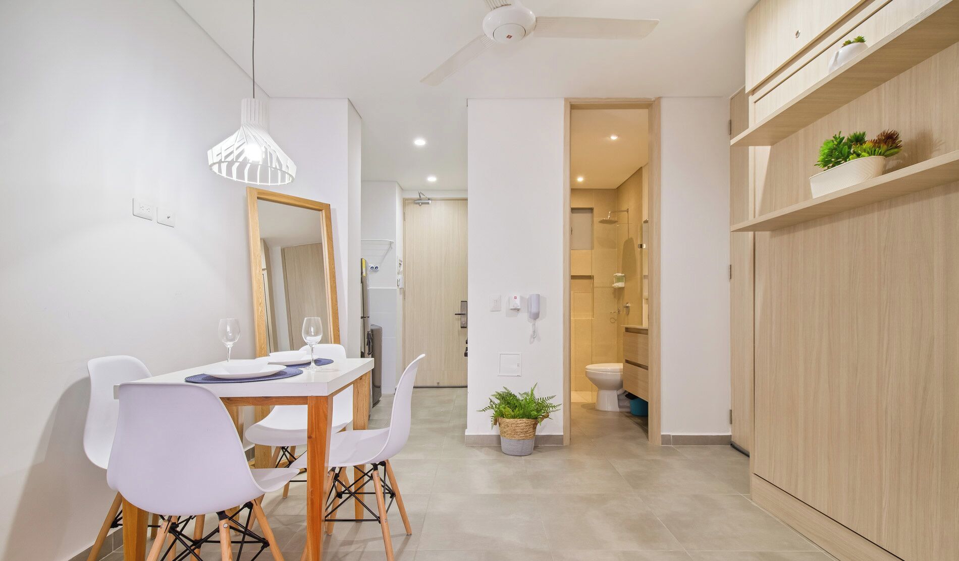 A modern kitchen with white cabinets, a dining table with chairs, and a hanging pendant light.