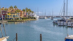 A marina with boats docked, a large yacht, and colorful buildings along the waterfront.