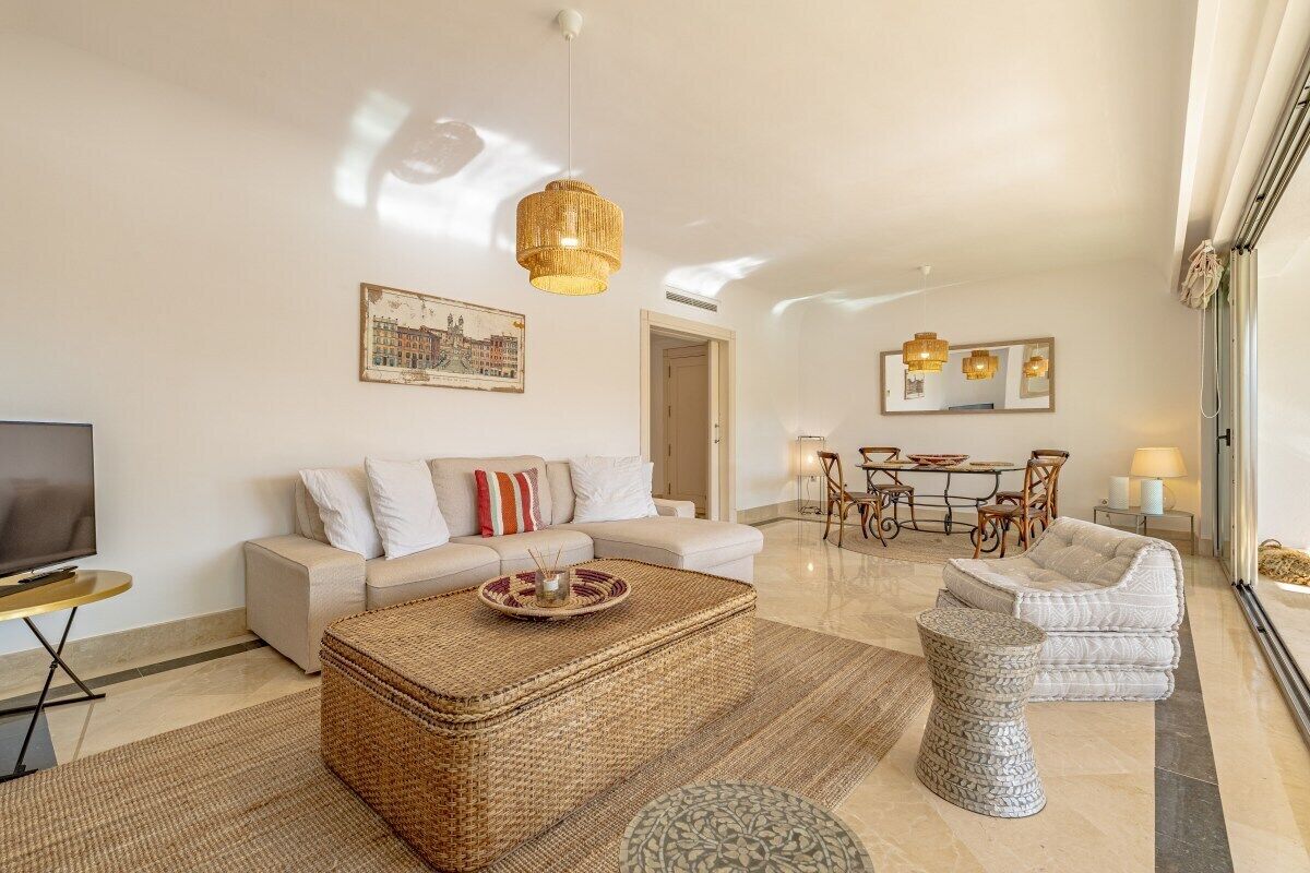 A spacious living room with a sofa, a coffee table, and a dining area with chairs and a table.
