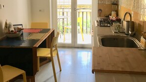 A compact kitchen with a dining area, a sink, and a view through the glass doors to the outside. - Cozy apartment 5 minutes from the metro, ideal for visiting Rome (Roma)
