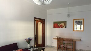 A living room with a sofa, coffee table, and a dining area with chairs and a table. - Cozy apartment 5 minutes from the metro, ideal for visiting Rome (Roma)