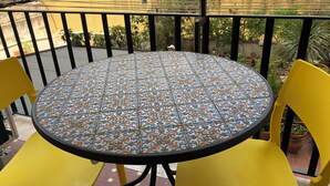 A round table with a patterned tablecloth, two yellow chairs, and a balcony railing. - Cozy apartment 5 minutes from the metro, ideal for visiting Rome (Roma)